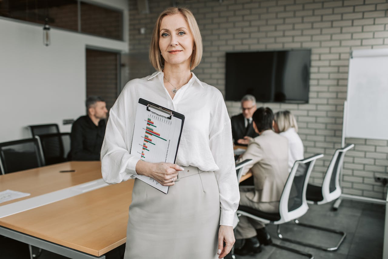 service-01 Professional businesswoman holding a clipboard during an office meeting, showcasing leadership in a corporate environment.