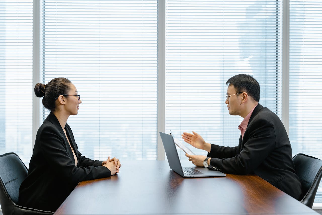 my-steps Two businesspeople engaged in a discussion during a professional meeting in an office setting.